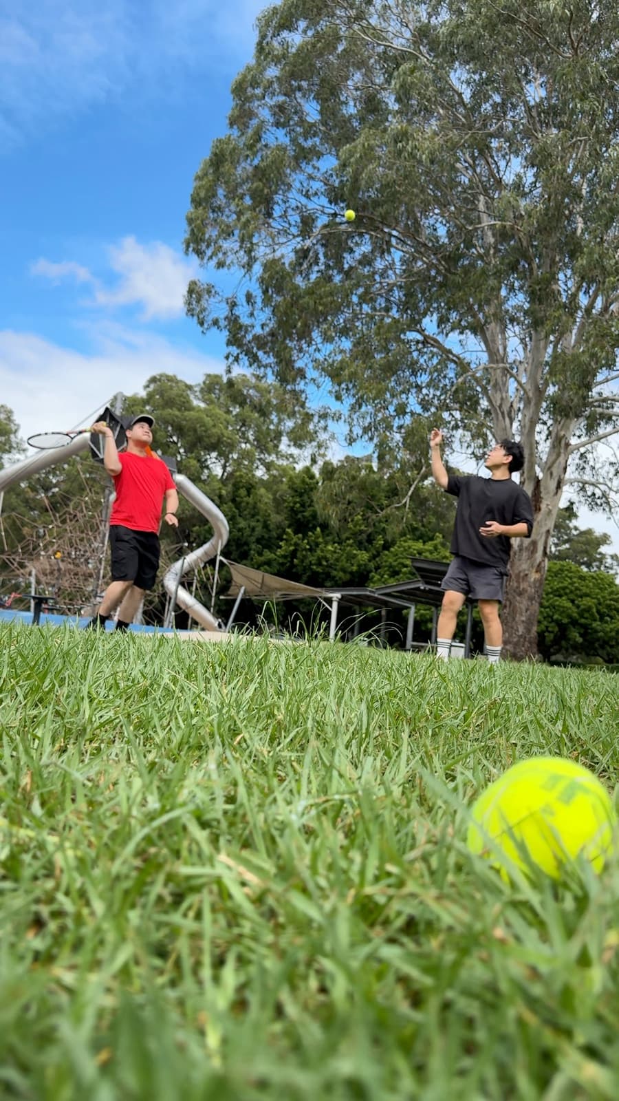 A Drift Health clinician coaching a participant's tennis swing on a grassy park court