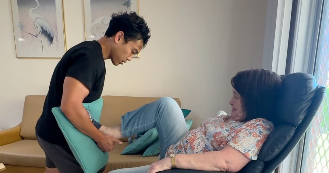 Drift Health physiotherapist supporting an older client’s leg during an in-home session