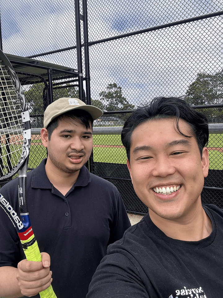Clinician and an adult smiling in a selfie at a tennis court, both holding racquets