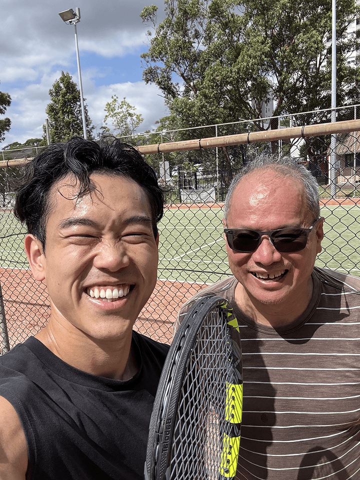 Clinician taking a selfie with a smiling older man in sunglasses at a tennis court