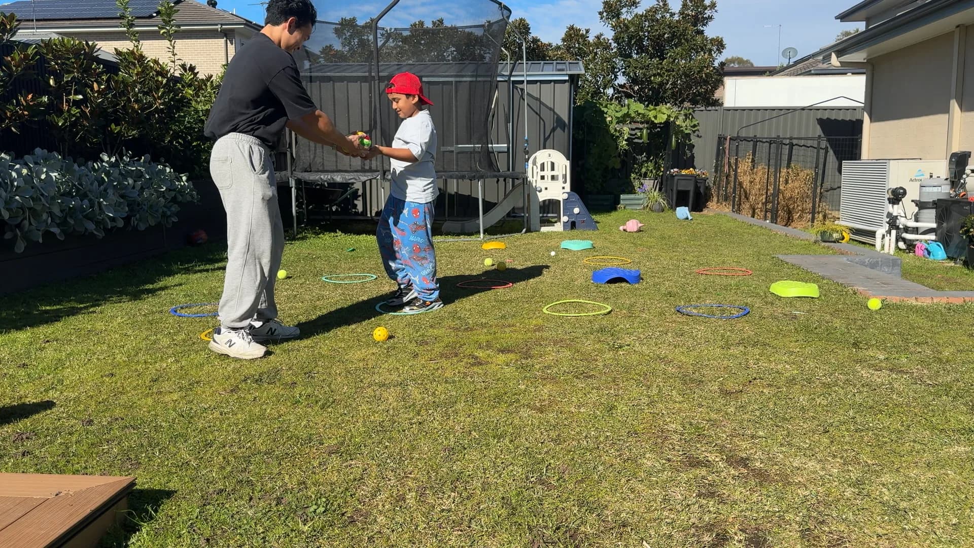 Clinician and child sharing a ball during a backyard activity