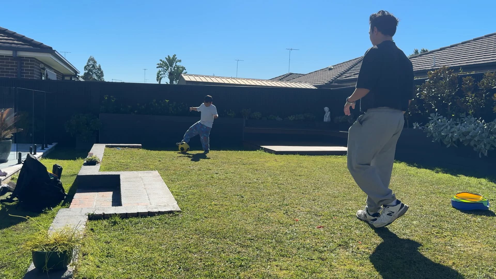 A participant practising soccer skills while Victor observes in the backyard