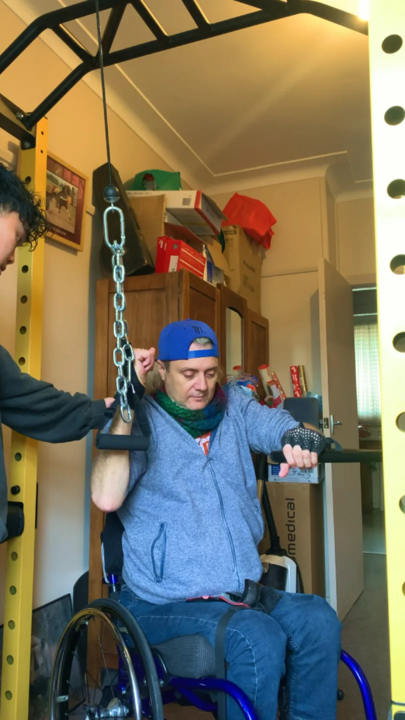 A wheelchair user completing an upper-body strength exercise at home