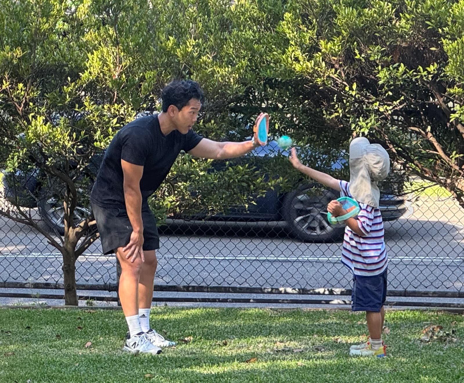 A Drift Health clinician holding up a pad for a young child to hit in the park