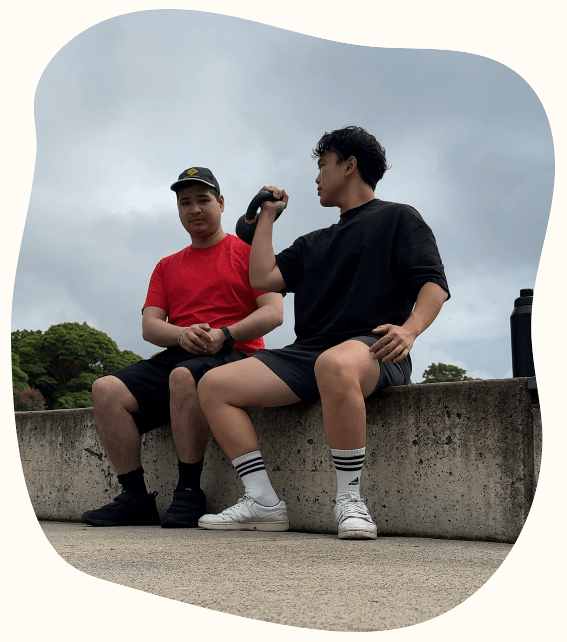 Two adults resting with a kettlebell after an outdoor exercise session
