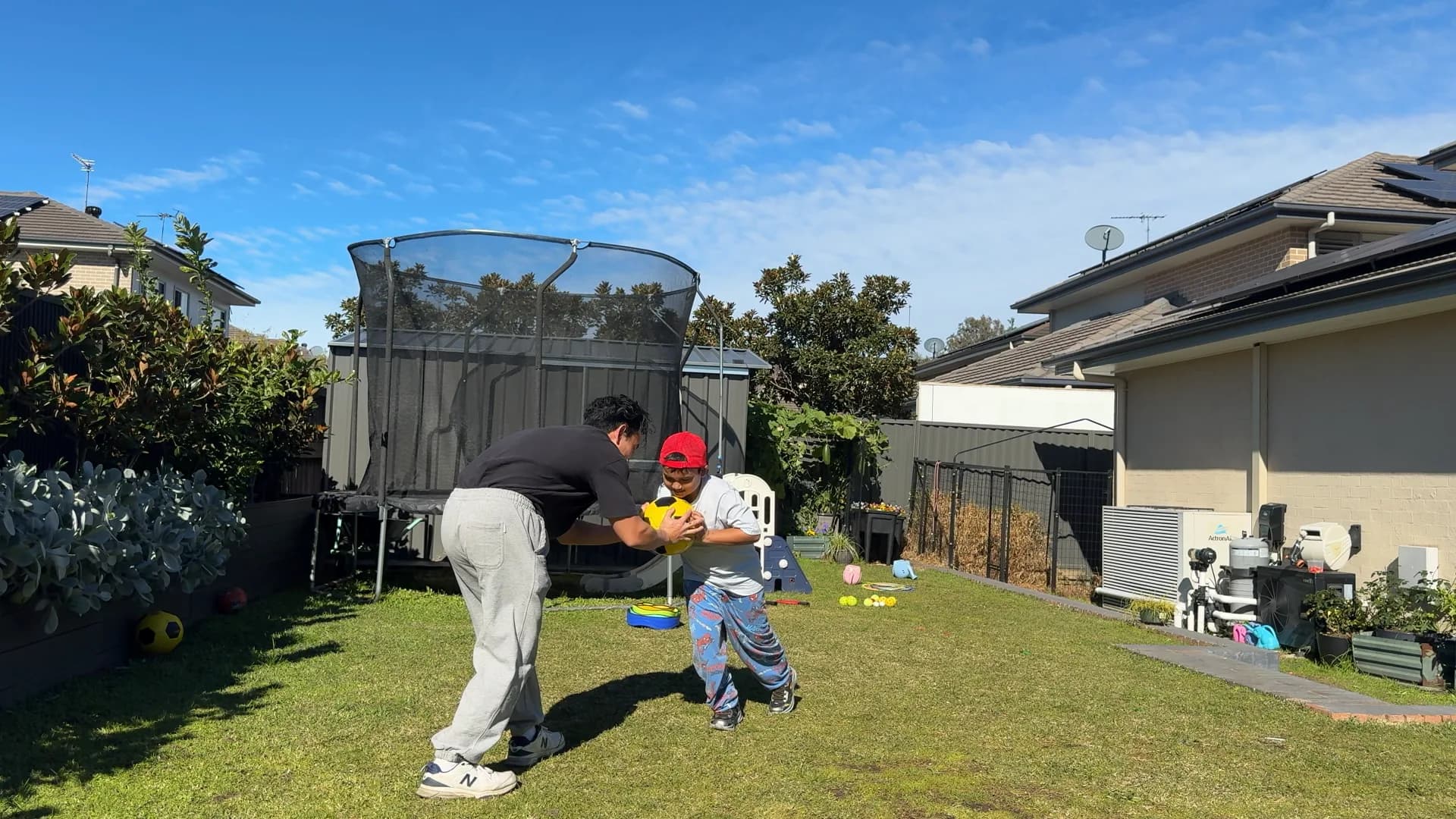 A child and therapist playing with a ball in the backyard