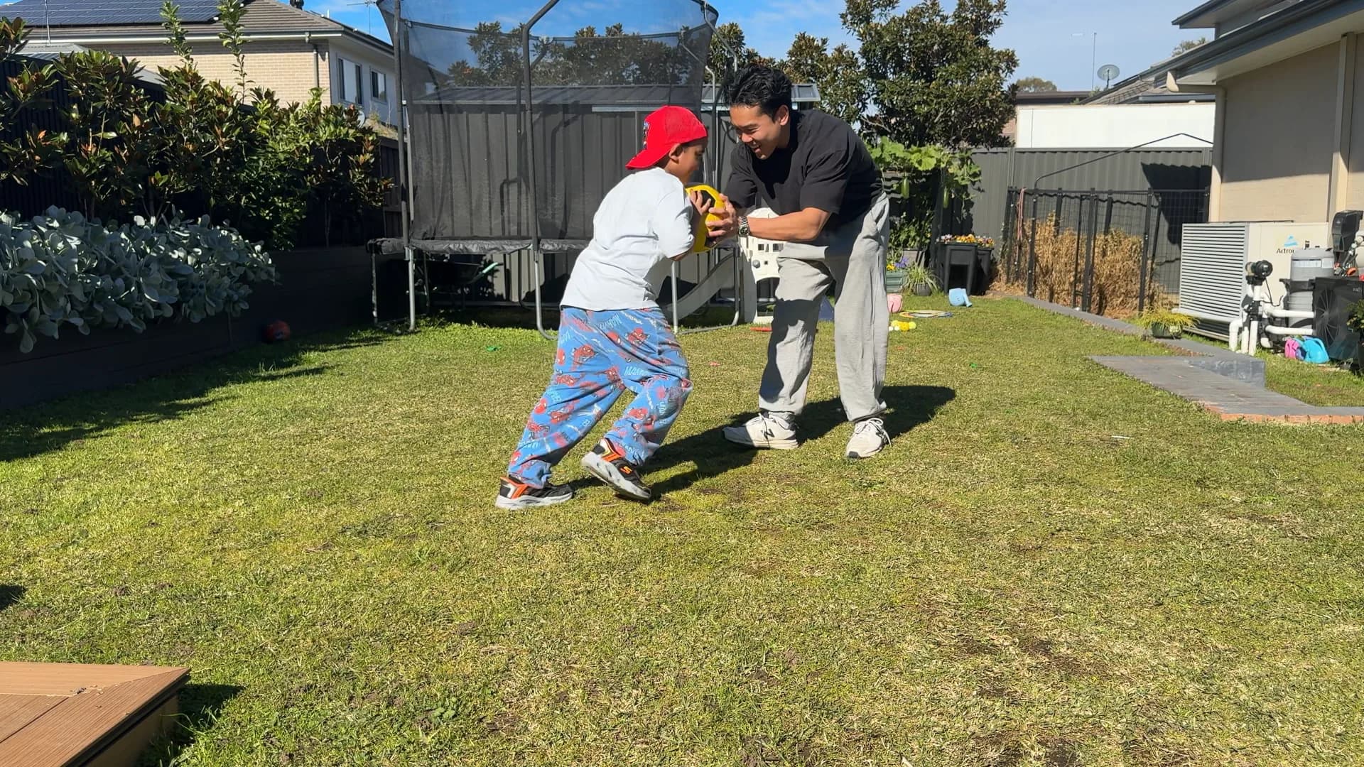 A child and therapist playing with a ball in the backyard