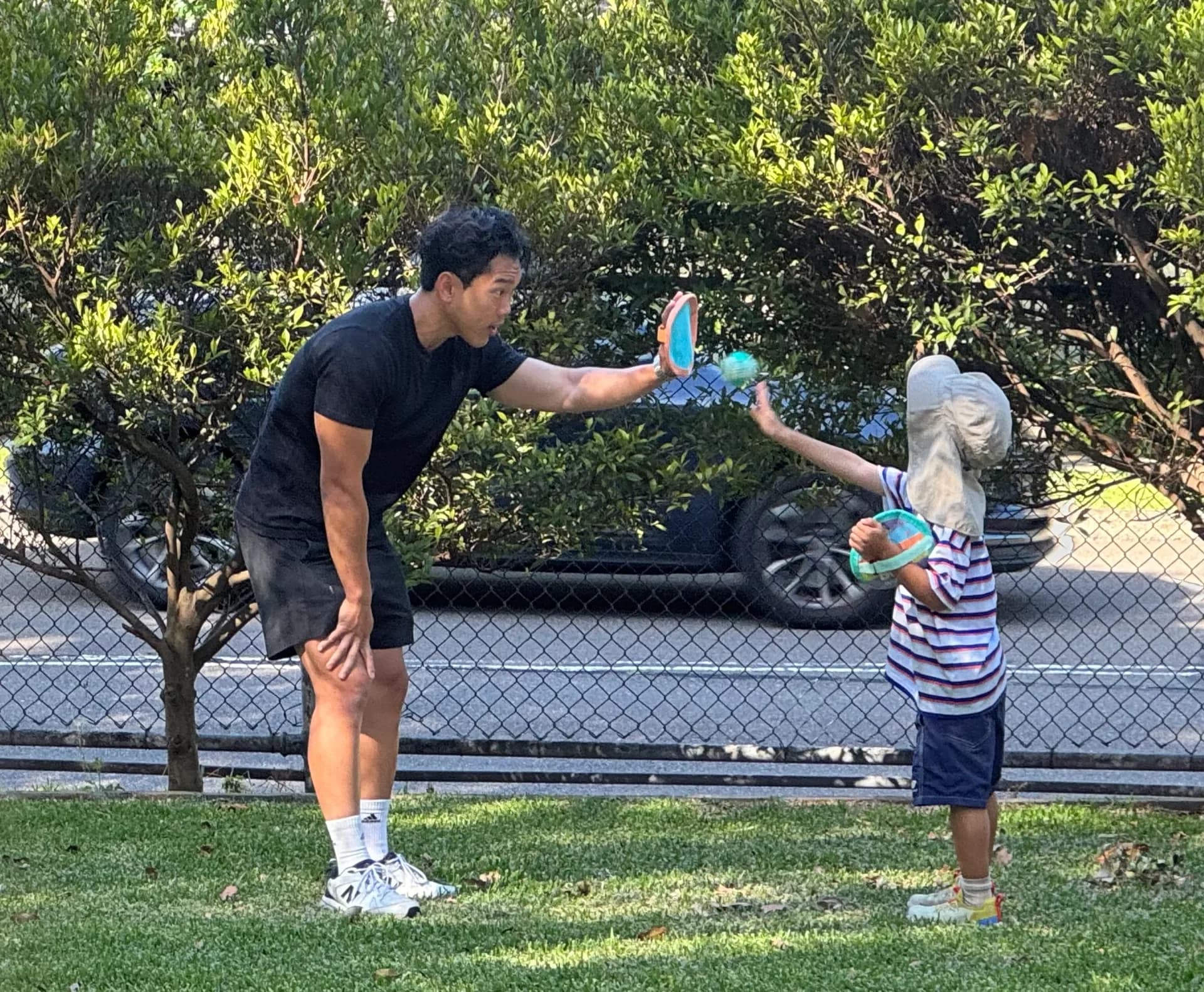 A child and adult playing catch with mitts in the park