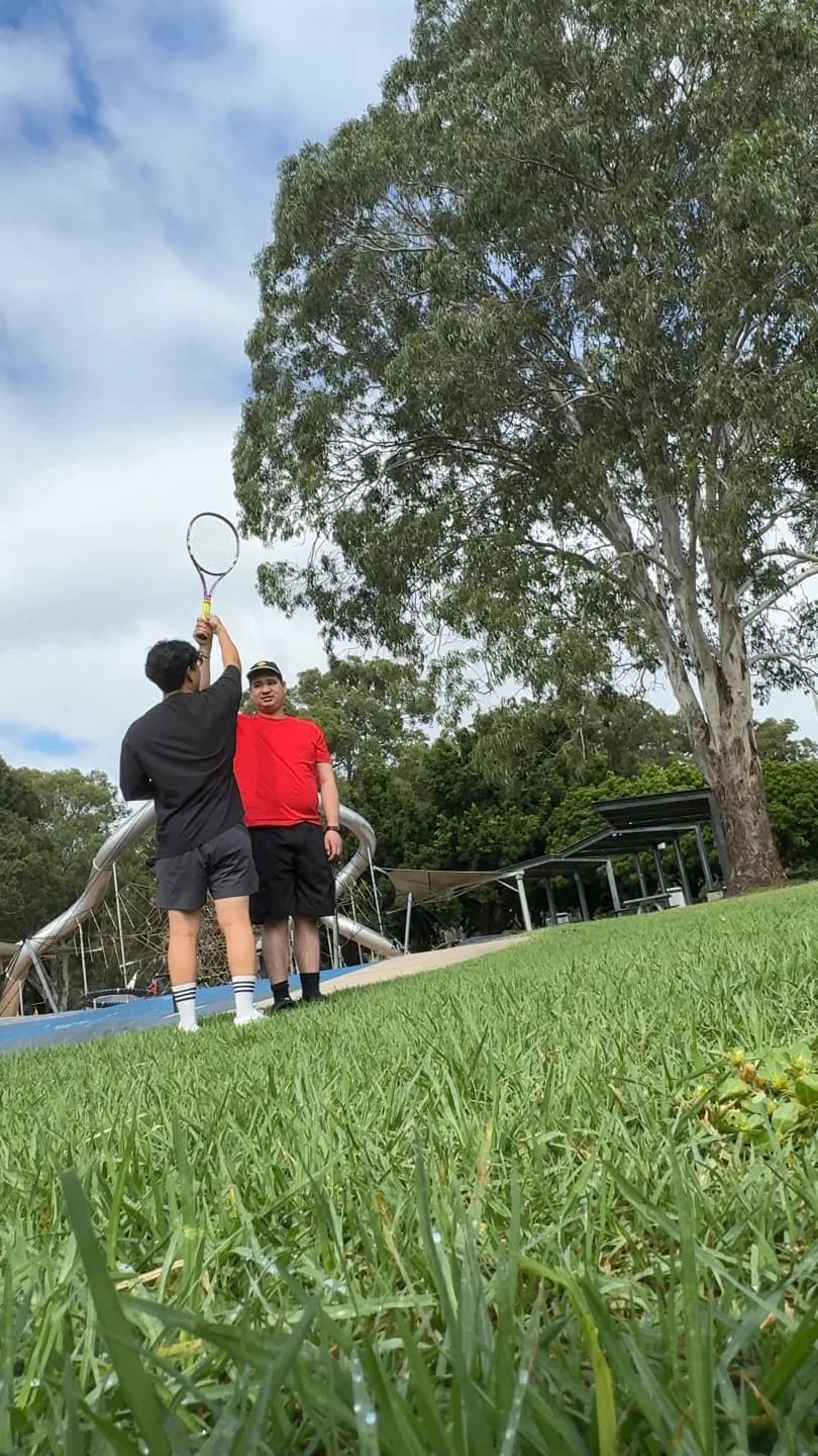 A clinician demonstrating a tennis movement in a park